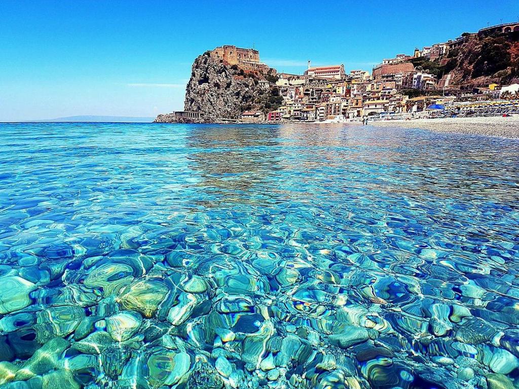 a beach with clear water and a city in the background at Scilla Beach in Scilla