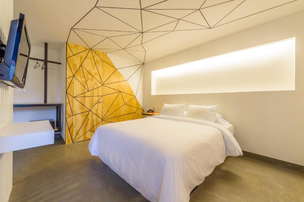 1 dormitorio con cama blanca y pared amarilla en Hotel El Peñon by Bithotels, en Cali