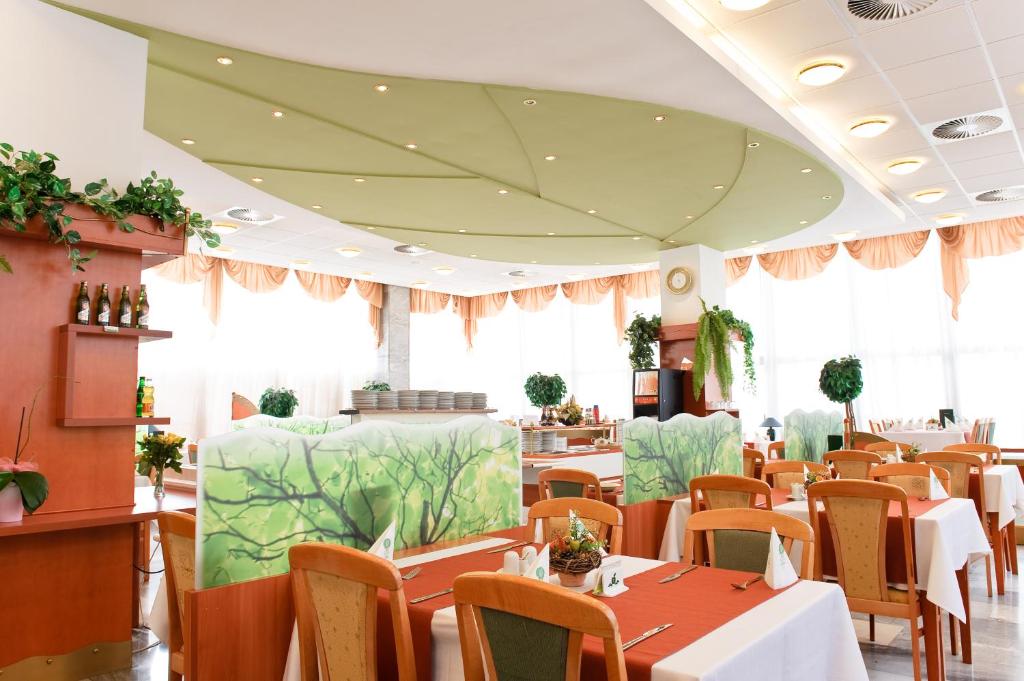 jadalnia ze stołami, krzesłami i oknami w obiekcie Hotel Flóra w Trenczyńskich Cieplicach