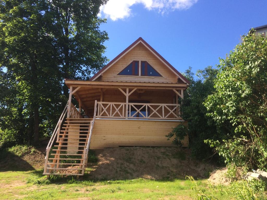 a small house with a porch and stairs to it at Domek w Sercu Mazur in Ryn