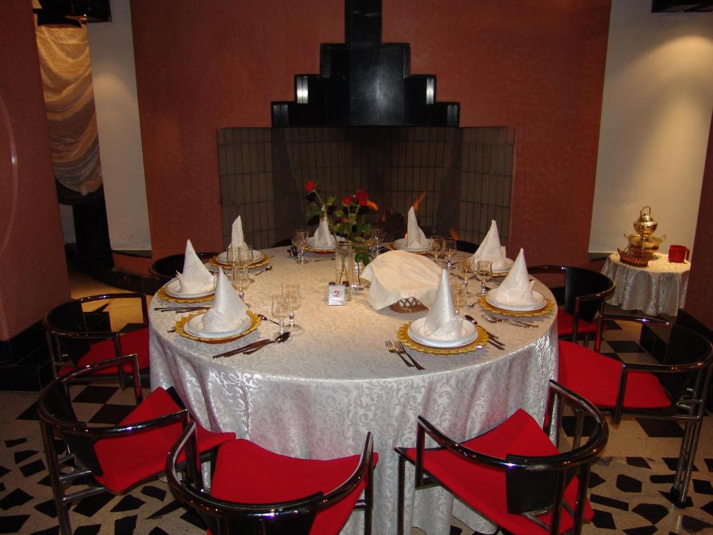 une table avec un tissu de table blanc et des chaises rouges dans l'établissement El Pueblo Tamlelt, à Agadir