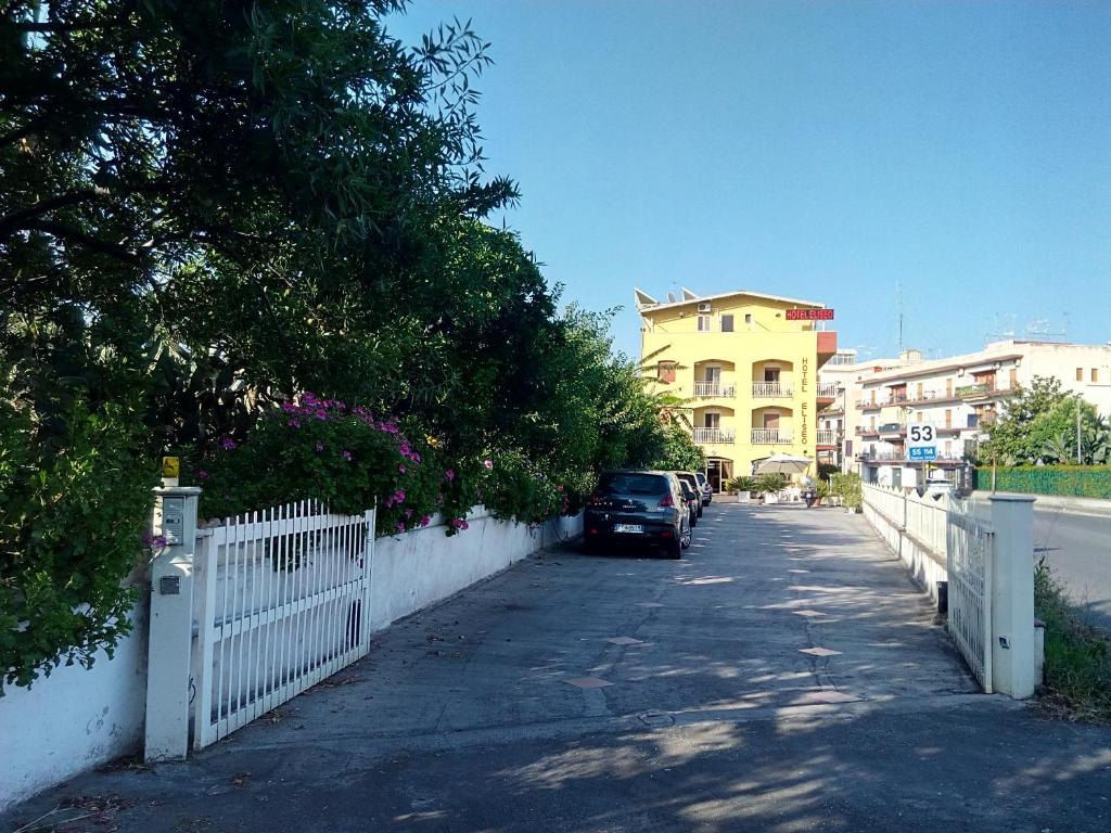 um carro estacionado numa rua ao lado de uma cerca branca em Hotel Eliseo em Giardini Naxos