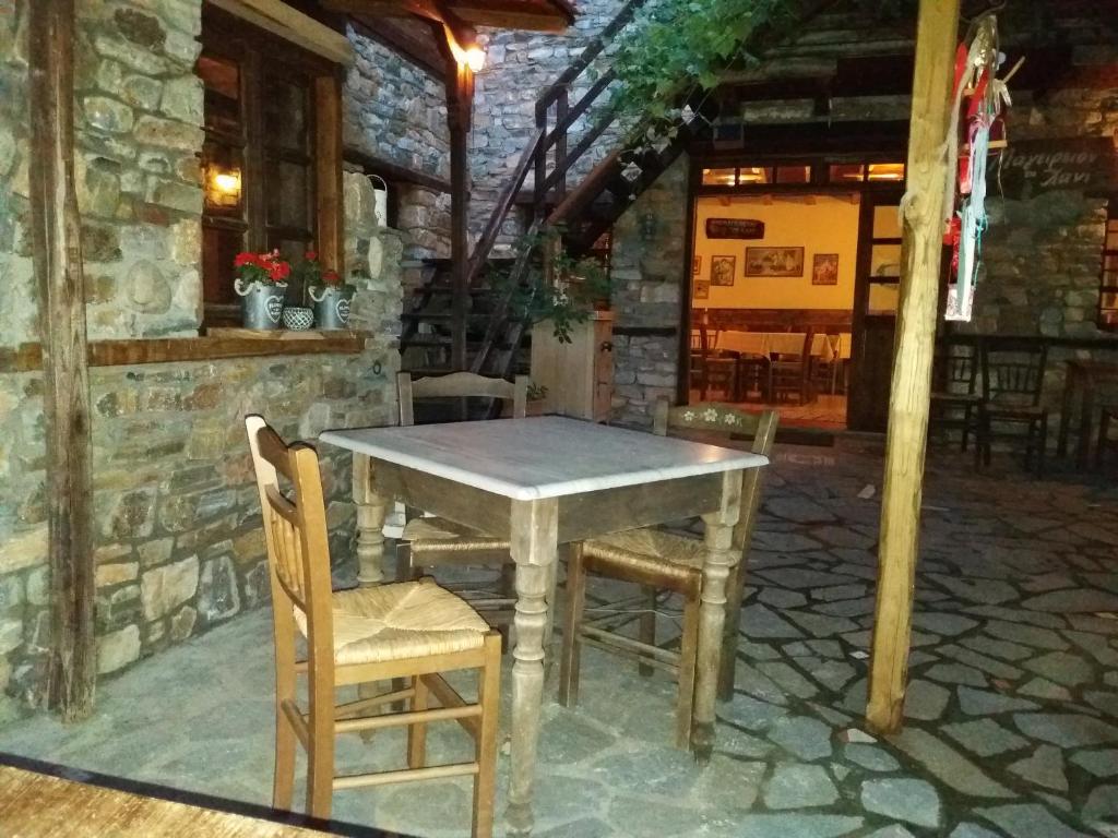 a wooden table and chairs in a stone house at To Xani in Palaios Panteleimonas