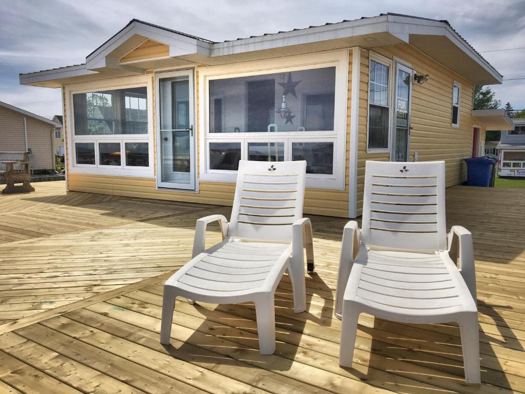 dos sillas blancas sentadas en una terraza frente a una casa en Chalet 44 en Grand Barachois
