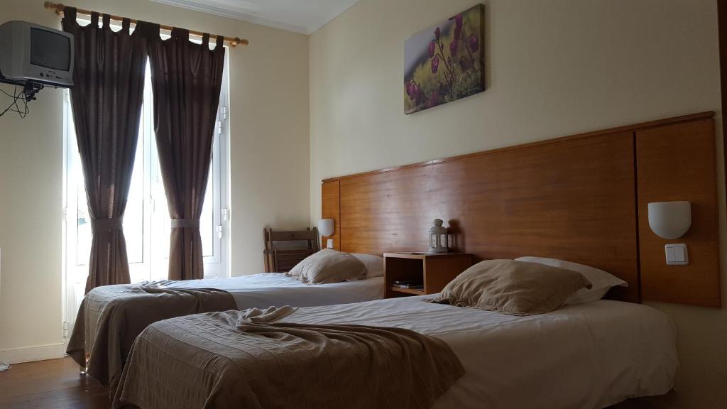 a bedroom with two beds and a large window at A Casa do Lado in Horta