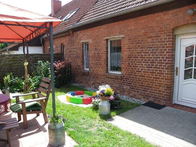 a brick house with a bench and an umbrella at Ferienwohnung-Familie-Hempel in Hohendorf
