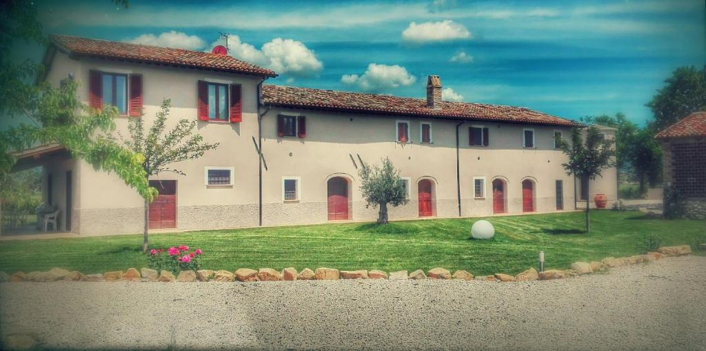 een groot wit huis met rode deuren en een tuin bij Podere Le Volte degli Angeli in Spello