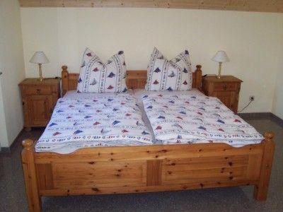 ein Holzbett in einem Schlafzimmer mit zwei Nachttischen in der Unterkunft Zur alten Schmiede II (Haus I) in Boltenhagen