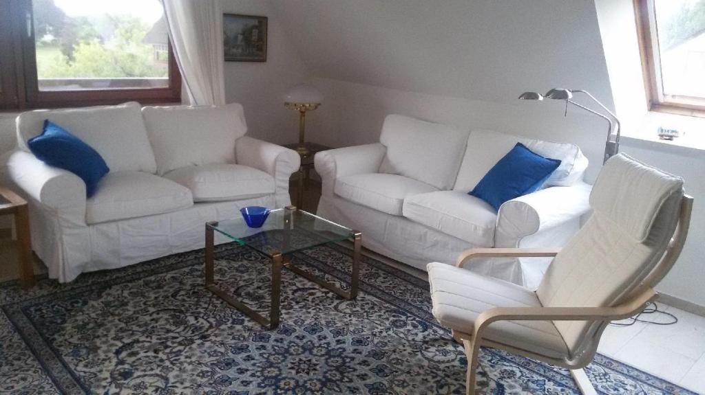 a living room with two white couches and blue pillows at Ferienwohnung-Gluecksburg in Ulsnis