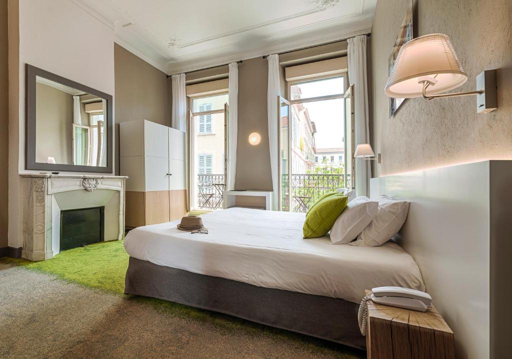 a bedroom with a large bed and a fireplace at Hôtel La Villa Tosca in Cannes