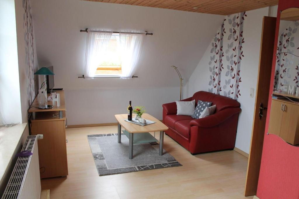 uma sala de estar com um sofá vermelho e uma mesa em Wohnung-2 em Oevenum