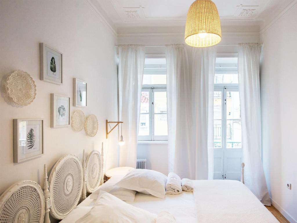 Cozy Lisbon Janelas Verdes في لشبونة: غرفة نوم مع طاولة بيضاء وكراسي ونافذة