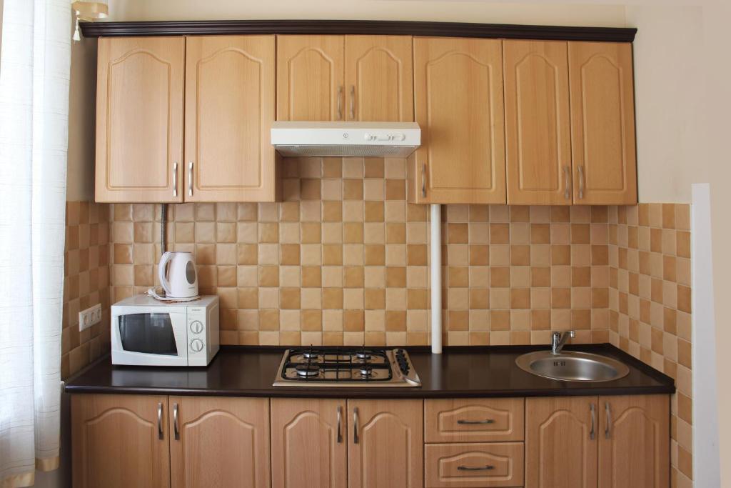 una pequeña cocina con armarios de madera y microondas en Apartments on Tsentralnaya Ploshad, en Kaliningrado