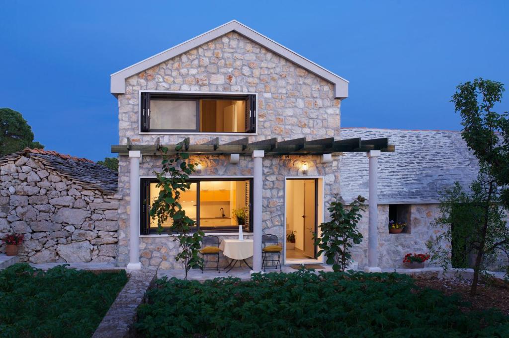 a stone house with a table and chairs in a yard at Holiday House KALIMERO in Primošten