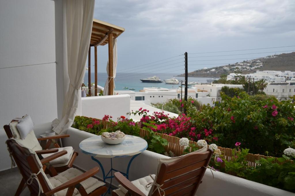 a balcony with a table and chairs and flowers at Studios Flora Manos in Platis Gialos