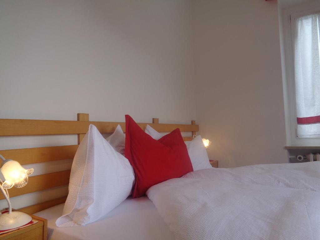 a bedroom with a bed with red and white pillows at Hotel Garni Suisse in San Martino di Castrozza