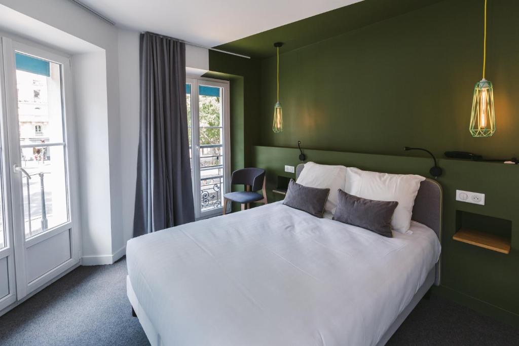 パリにあるル プティ コージー オテルの緑の壁のベッドルーム1室(白いベッド1台付)