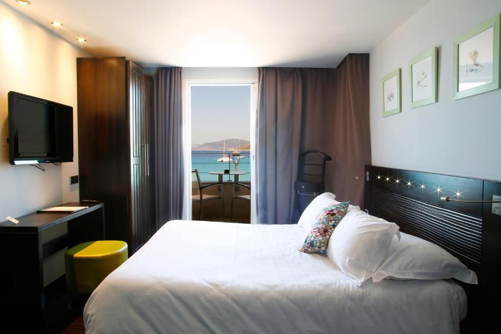 a hotel room with a bed with a view of the ocean at L&#39;Escale Côté Sud in LʼÎle-Rousse