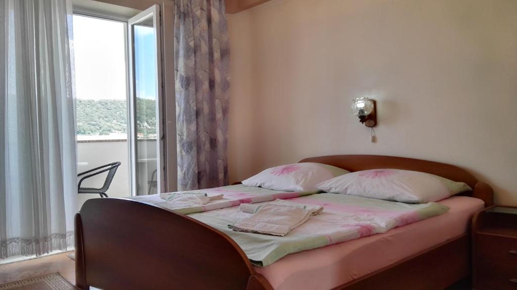 una camera da letto con un letto con lenzuola rosa e una finestra di Ljubica Apartments and Rooms a Rab