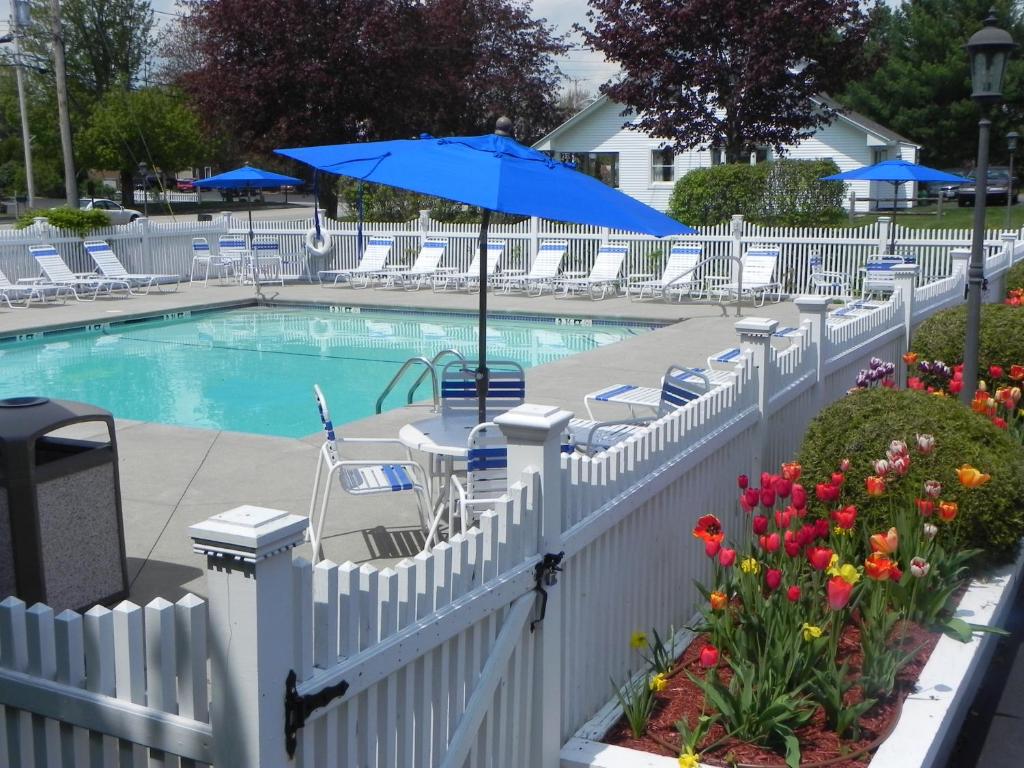 une clôture blanche autour d'une piscine avec un parasol bleu dans l'établissement Elmwood Resort Hotel, à Wells