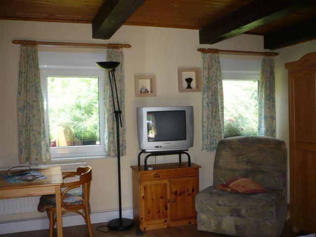 a living room with a tv and a chair and a desk at Pension-Drews-Ferienzimmer-3 in Grubenhagen