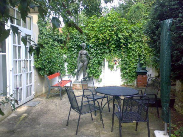 eine Terrasse mit einem Tisch, Stühlen und einer Statue in der Unterkunft Ferienwohnung Franziska Wünsche, Wohnung 1 in Dresden