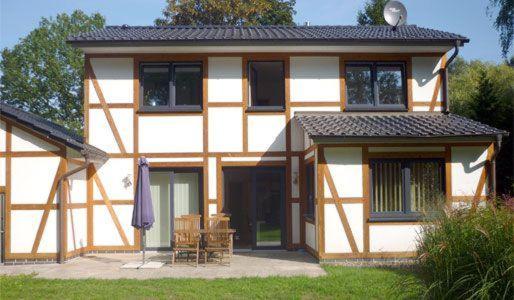 una casa con sombrilla y sillas delante en Ferienwohnung-Draeger, en Mardorf