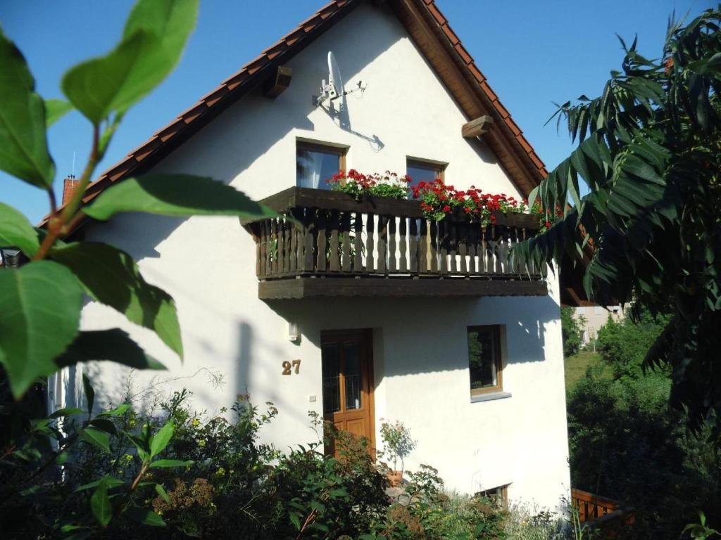 ein weißes Haus mit einem Balkon mit Blumen darauf in der Unterkunft Ferienwohnung Mund in Pillnitz