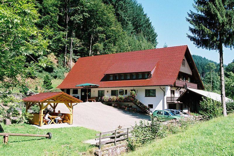 ein Haus mit rotem Dach und einem Auto vor dem Haus in der Unterkunft Hinterkimmighof in Oberharmersbach
