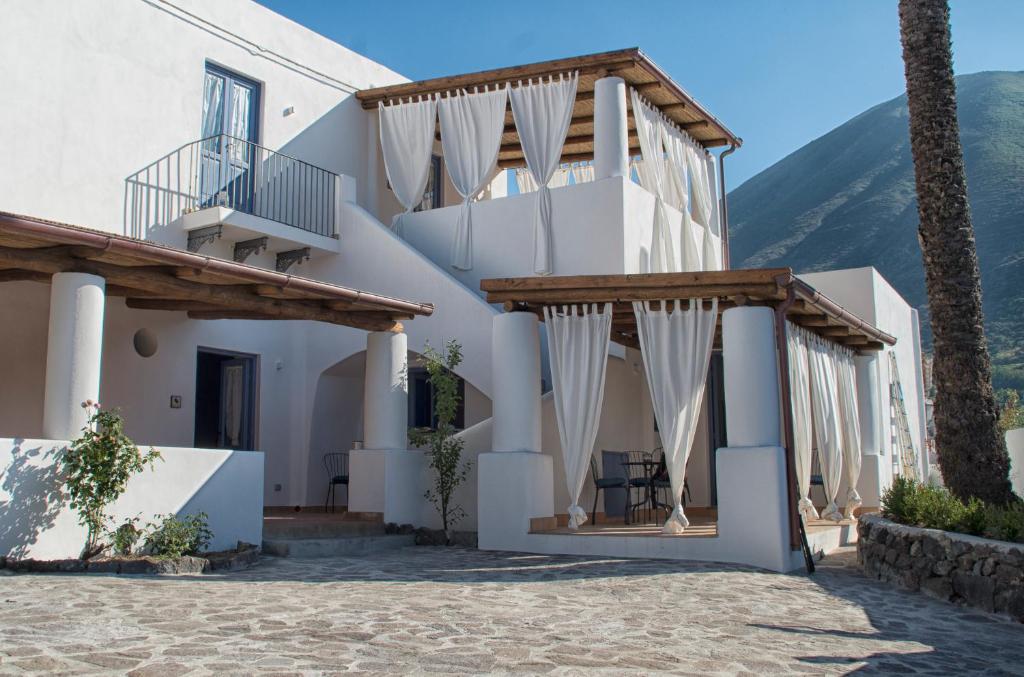 un edificio bianco con balcone e palma di Le Sette Perle a Malfa