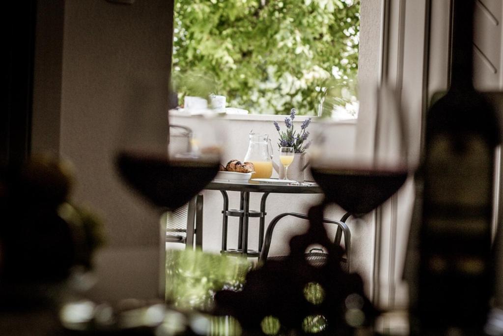 - une vue sur une table avec des verres à vin dans la fenêtre dans l'établissement Apartman Dujmović, à Split