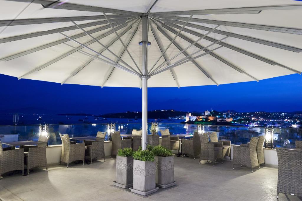 un restaurant avec un parasol, des tables et des chaises dans l'établissement Ena Boutique Hotel, à Bodrum City