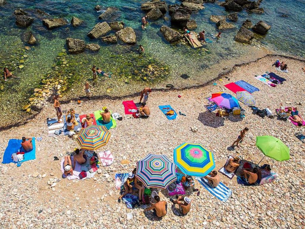シラクーサにあるTalia Ortigia Apartmentの傘を持って浜辺に横たわる人々