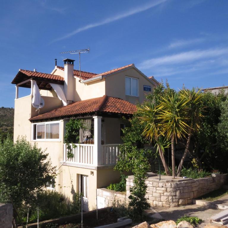 a house with a balcony and palm trees at Apartmani Rita in Milna
