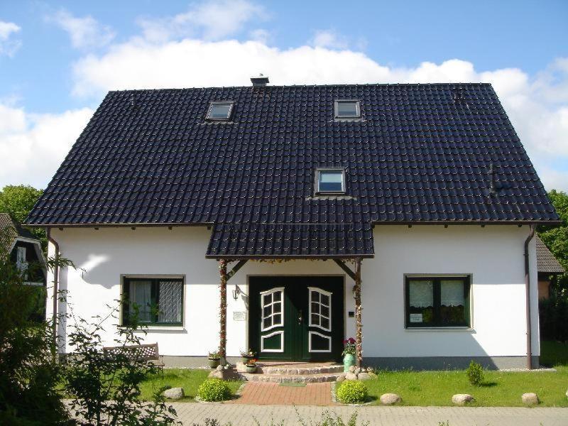 ein weißes Haus mit schwarzem Dach in der Unterkunft Ferienwohnung Melina in Binz