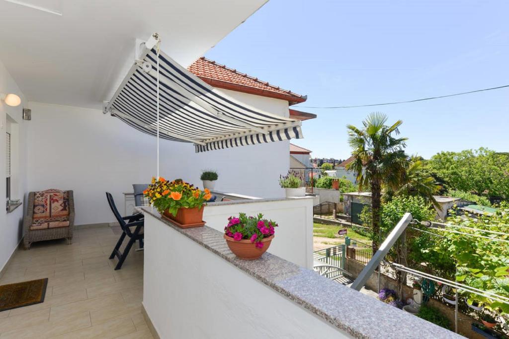 a balcony with two potted plants and an umbrella at Apartment Vesna in Zadar