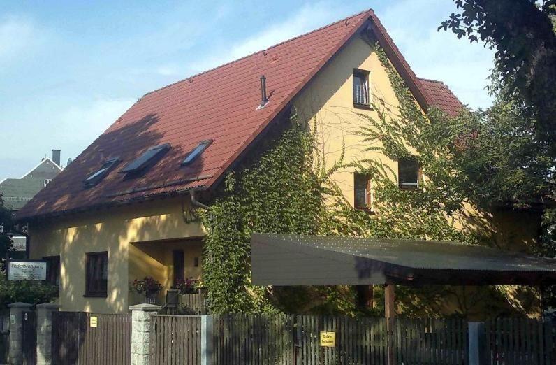 ein Haus mit einem roten Dach mit einem Zaun in der Unterkunft Ferienwohnung Illgen in Dresden