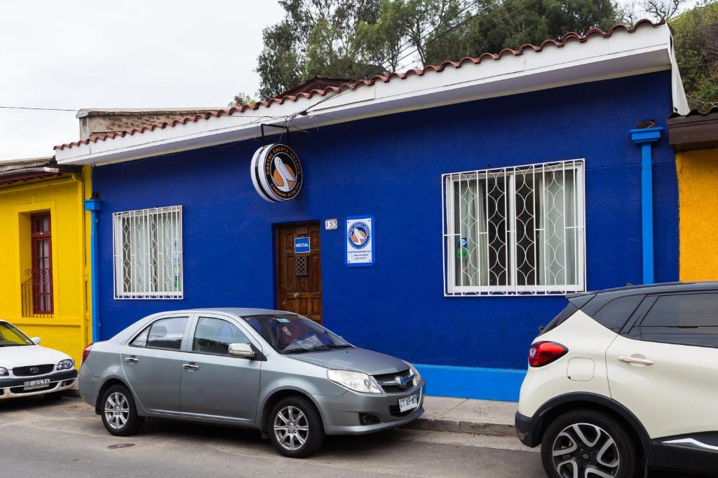 dos autos estacionados frente a un edificio azul en Hostal Caleta Abarca, en Viña del Mar