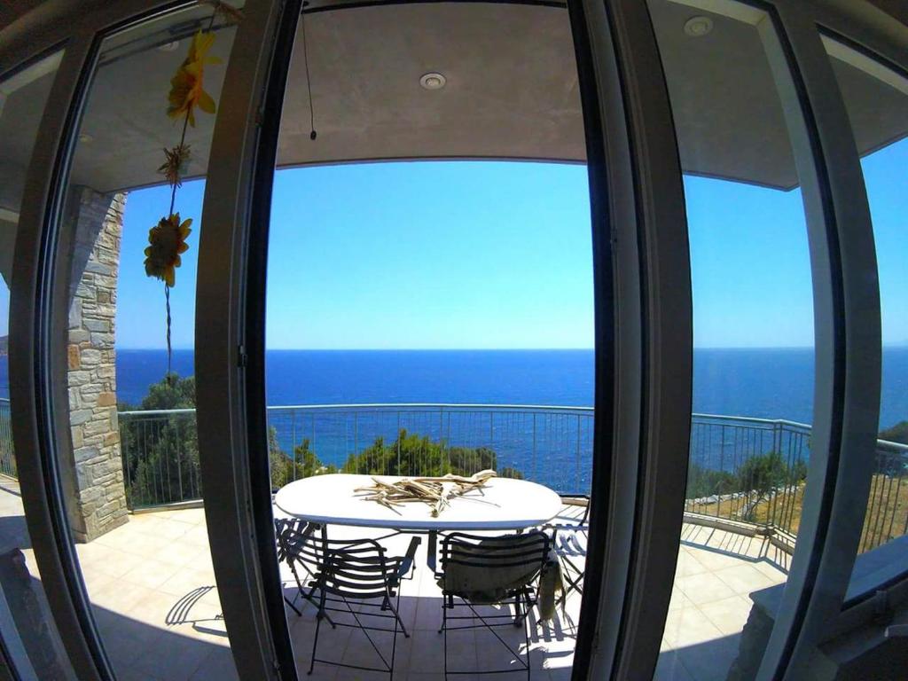 a table and chairs on a balcony with a view of the ocean at Villa Aegean Balcony in Akhladherí