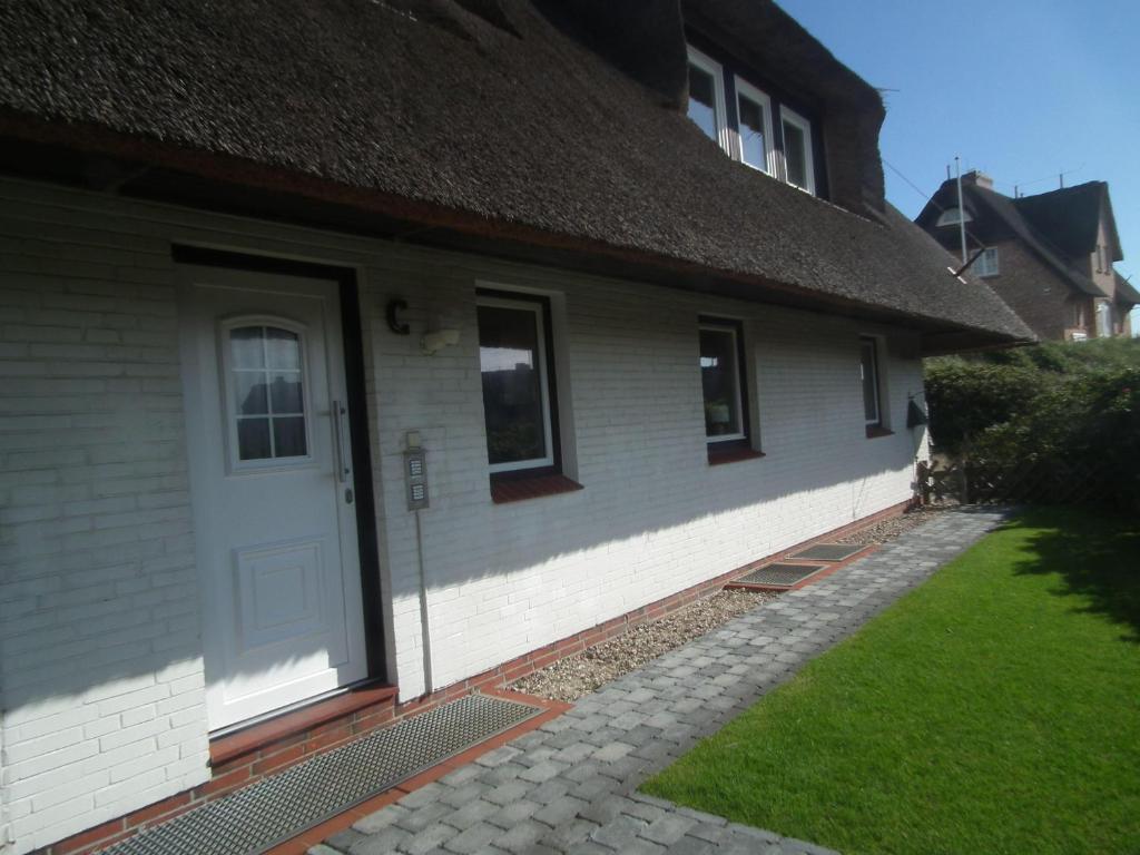 una casa con una puerta blanca y un patio de césped en Haus-Marina, en Rantum