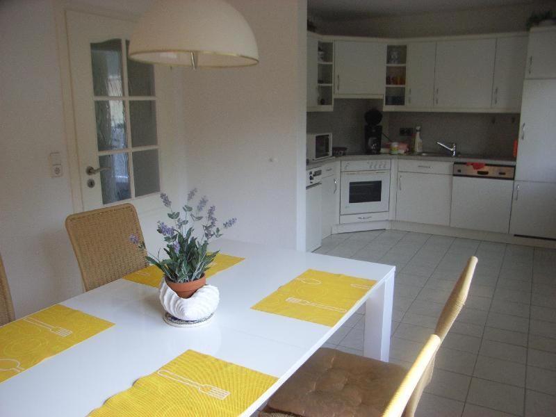 a kitchen with a white table with a vase of flowers on it at Andrea-EG in Büsum