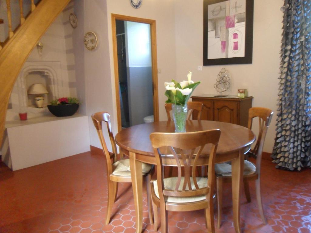 a dining room table and chairs with a vase of flowers on it at Auberge a la Ferme in Surques