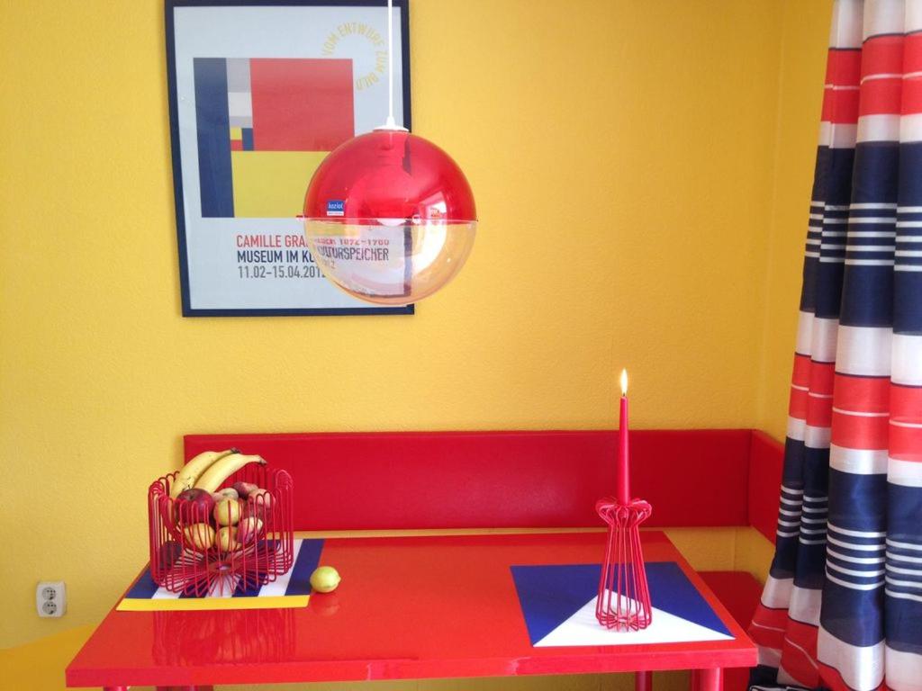 un banco rojo con una vela y una mesa roja en Direkt am Main en Karlstadt