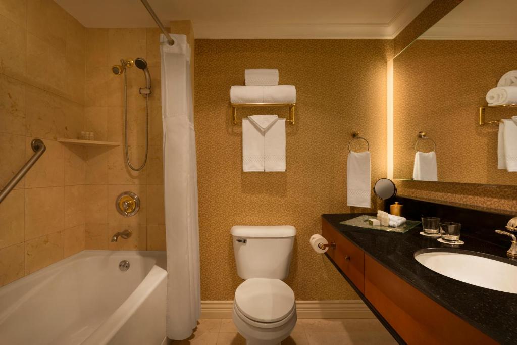 a bathroom with a toilet and a tub and a sink at Hotel Le Soleil by Executive Hotels in Vancouver