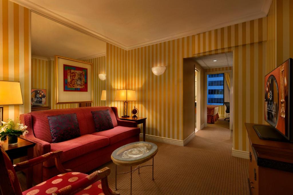 a living room with a red couch and a table at Hotel Le Soleil by Executive Hotels in Vancouver