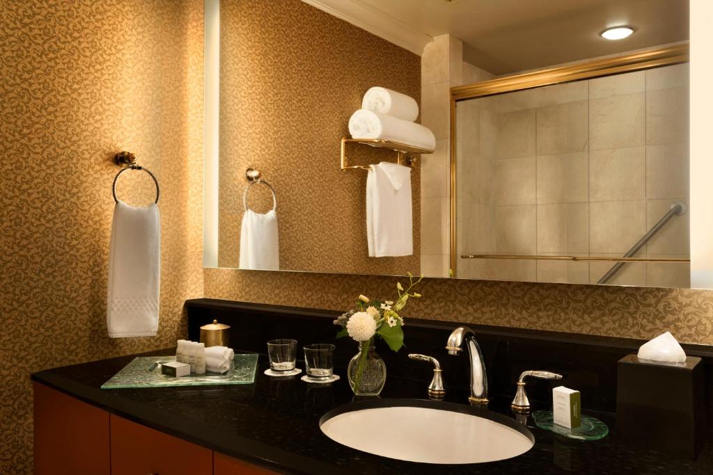 a bathroom with a sink and a mirror at Hotel Le Soleil by Executive Hotels in Vancouver