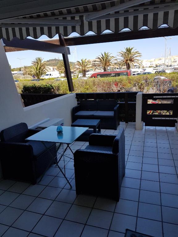 un patio avec tables, chaises et palmiers dans l'établissement Port nature, au Cap d'Agde