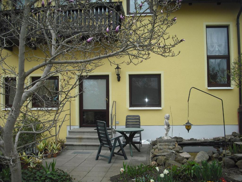 ein gelbes Haus mit einem Tisch und Stühlen davor in der Unterkunft Ferienwohnung der Familie Thierse in Stolpen