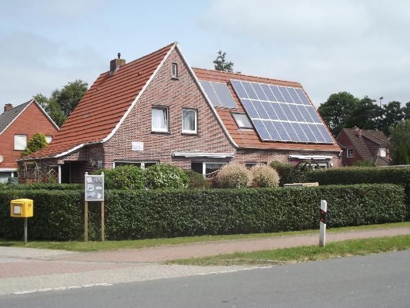 ein Haus mit vielen Sonnenkollektoren darauf in der Unterkunft Ferienhäuser MoJe 1 in Dornum