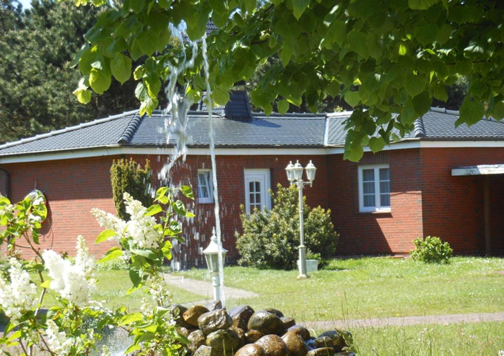 a house with a water fountain in front of it at Bungalow-Lerchennest in Wittdün